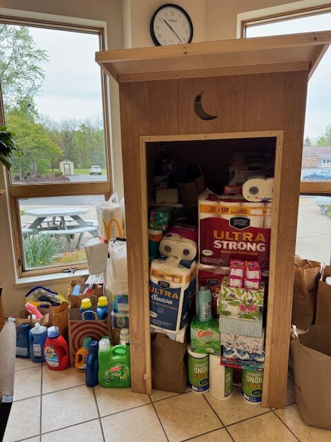 a photo of the outhouse deployed at a collection site brimming with toiletries and other donated supplies