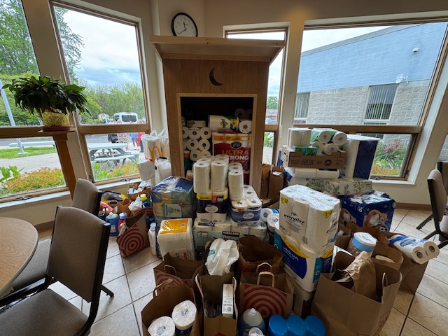 a photo of the outhouse deployed at a collection site brimming with toiletries and other donated supplies
